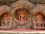 Kathmandu Changu Narayan 34 Three Images Of Vishnu, One Riding Garuda, On West Side Of Parijat Tree Platform On North East Side Of Changu Narayan Three statues of Vishnu are on the west side of the parijat tree platform in the north east area of Changu Narayan. The middle Vishnu holds a chakra wheel and a long mace club in his raised hands and is shown riding Garuda. Each of the left and right Vishnus hold a chakra wheel and a mace club, standing between two smaller figures.